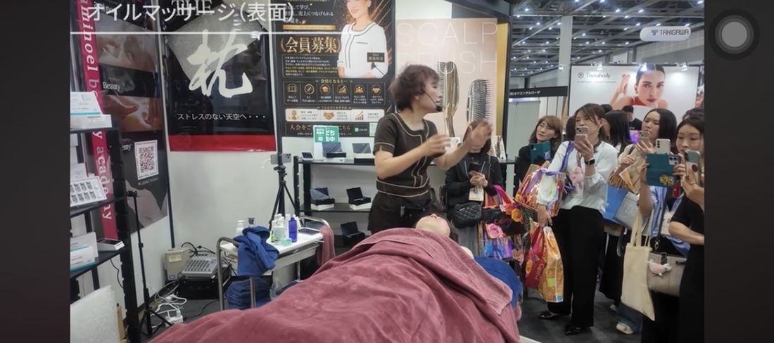 Beautyworld Japanのブースに多くの来場者が集まりAmyの実演を見学・撮影する様子
