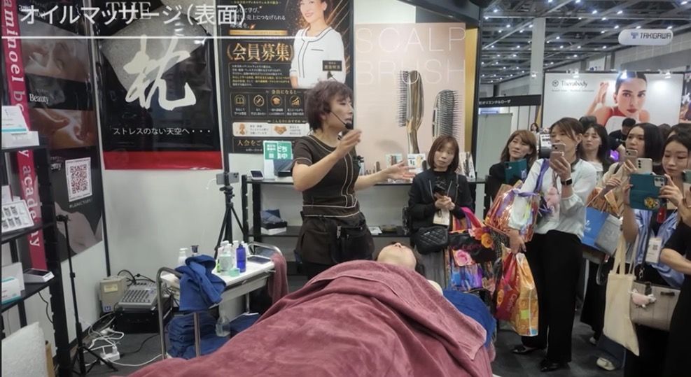 Beautyworld Japan会場でAmyが実演を行い来場者が見学する様子と会場全体の熱気